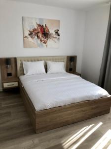 Modern and New Apartments in North of Timisoara - PNM Residence في Uisenteş: غرفة نوم بسرير كبير مع شراشف بيضاء
