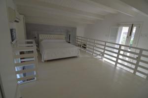 a white bedroom with a bed and a balcony at Il pesce nero in Portopalo