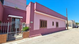 a pink building with a fence in a street at Casa Rosa in Sogliano Cavour