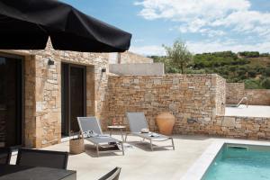 a patio with two chairs and a swimming pool at Fari Stone Villas in Skala Marion