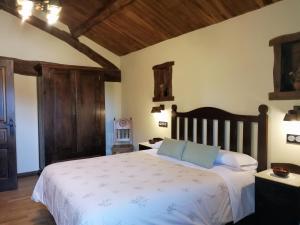 a bedroom with a large bed with white sheets and blue pillows at Pajar in Braña