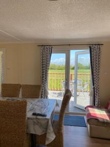 a living room with a table and chairs and a patio at Lodges at Bryncarnedd, Aberystwyth in Aberystwyth +10 photos