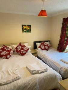 a room with two beds with red and white pillows at Lodges at Bryncarnedd, Aberystwyth in Aberystwyth
