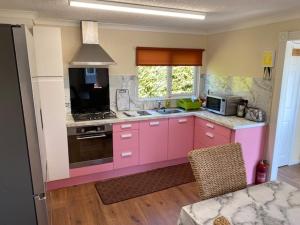 a kitchen with pink cabinets and a stove top oven at Lodges at Bryncarnedd, Aberystwyth in Aberystwyth