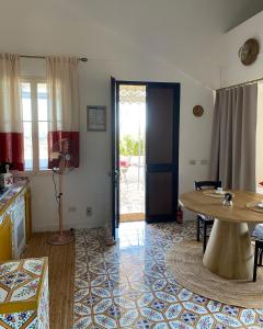a living room with a table and a door to a patio at Dammuso Pensare alla Luna in Pantelleria