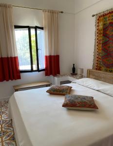a bedroom with two white beds and two windows at Dammuso Pensare alla Luna in Pantelleria