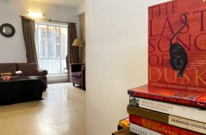 a stack of books in a living room at The Aster Homestay - Bedrooms & Apartments in Kolkata
