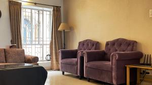 een woonkamer met 2 stoelen en een raam bij The Aster Homestay - Bedrooms & Apartments in Calcutta