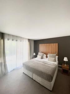 a bedroom with a large bed and a large window at Hotel Au Bon Coin du Lac in Mimizan