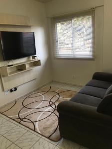 ein Wohnzimmer mit einem Sofa und einem Flachbild-TV in der Unterkunft Apartamento foz centro 03 in Foz do Iguaçu