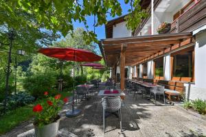 un patio con mesas, sillas y una sombrilla en Hotel Ruchti - Zeit für mich en Füssen