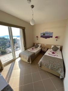 Dos camas en una habitación con una gran ventana. en Talay Pansiyon, en Kas