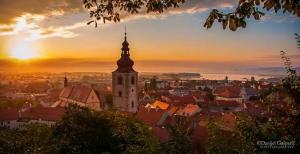 a view of a city with a church tower at sunset at Hotel Mitra, Story Hotels in Ptuj