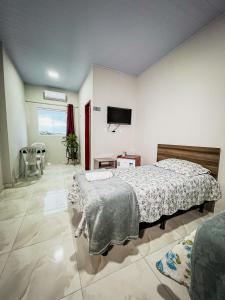 Serra de São Bento的住宿－Pousada Serrana，卧室配有一张床,墙上配有电视。