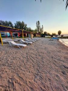 una fila di sedie a sdraio su una spiaggia sabbiosa di Vik Son Family Beach a Sevan