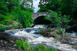 un pont en pierre sur une rivière avec des rapides dans l'établissement Munkedals Herrgård, à Munkedal