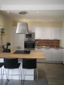 eine Küche mit einer Theke mit Stühlen und einer Mikrowelle in der Unterkunft Appartement contemporain le Vendome à 90m de la plage in Le Grau-du-Roi