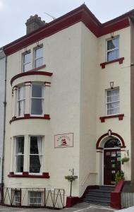 a white house with a red door and stairs at Ashfields in Llandudno