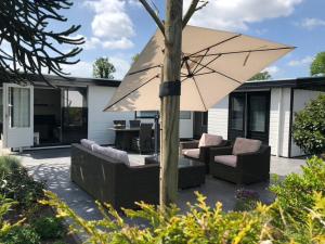 un patio con 2 sillas y una sombrilla en Vakantiehuis “Het Zeepaard”, en Voorthuizen