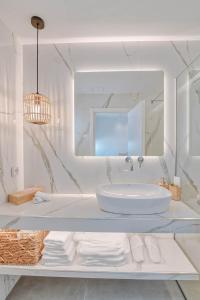 uma casa de banho branca com um lavatório e um espelho em Nautica suites - Executive suite with jacuzzi em Antiparos Town