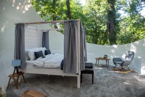 een slaapkamer met een hemelbed en een stoel bij Nomád Glamping in Noszvaj