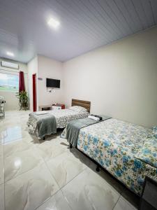 a room with two beds and a flat screen tv at Pousada Serrana in Serra de São Bento