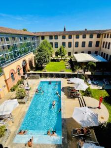 a large swimming pool with people in a hotel at Abbaye des Capucins Spa & Resort in Montauban