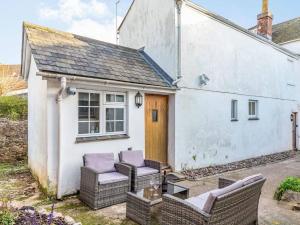 a white cottage with two chairs and a table at Lovely Heather and Primrose Villa 1 double, 1 double sofa, 6 single, and 1bunk bed in Torquay