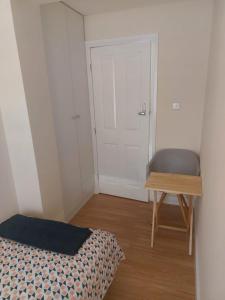 a bedroom with a bed and a table and a door at Single Room only for one adult in Southall