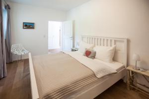 - une chambre avec un grand lit blanc et des oreillers blancs dans l'établissement Kitz Apartments, à Kitzbühel