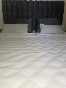 a large white bed with a black headboard and white pillows at Marina Golf Asilah Vue mer et golf in Asilah