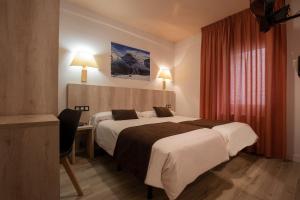 Habitación de hotel con 2 camas y escritorio en Hotel Marco Polo en La Massana