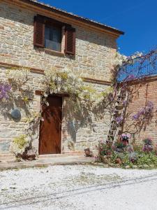 un edificio de ladrillo con una puerta de madera y flores en Casale San Martino Agriturismo Bio, en SantʼAngelo in Pontano