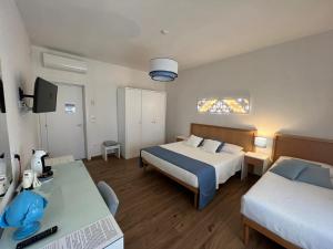 a bedroom with two beds and a desk with a television at B&B Venti di Mare in Otranto