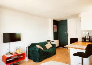 een woonkamer met een groene bank en een keuken bij Loueurdappart - Studio Cosy, Très jolie Vue Mer, Tout à pied à la Baule in La Baule