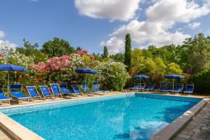uma piscina com cadeiras azuis e guarda-sóis em Trilo Begonia em Marina di Grosseto