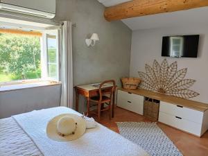 1 dormitorio con cama y escritorio con sombrero en La Ferme Les Eybrachas, en Réauville