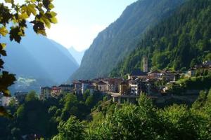 une ville sur une colline avec des montagnes en arrière-plan dans l'établissement Appartamento Vanoi nel cuore verde del Trentino, à Canal San Bovo