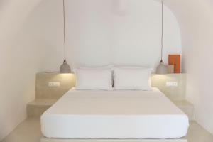 1 cama con sábanas blancas y almohadas en una habitación en Kyrkos Residency by SV en Oia