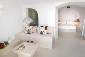Habitación blanca con cama y mesa en Kyrkos Residency by SV, en Oia
