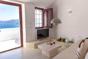 sala de estar con sofá y mesa con copas de vino en Kyrkos Residency by SV, en Oia