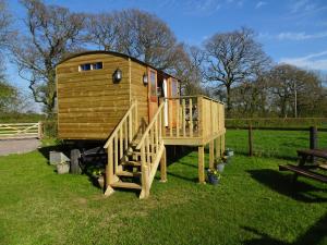 a large wooden house with a staircase and a deck at The Lazy Shepherd in East Pennard