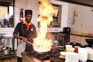 Un hombre en una cocina con fuego sobre un pastel. en Golden Palace Hotel, en Eldoret
