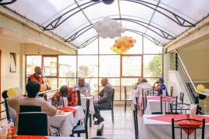 a group of people sitting at tables in a restaurant at Golden Palace Hotel in Eldoret