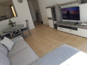 sala de estar con sofá, TV y mesa en Corvera Golf Holiday Home en Murcia