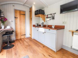 uma cozinha com armários brancos e uma bancada em The Moorhen Retreat em Oswestry
