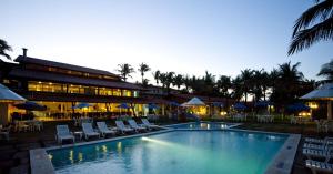 una piscina con sillas y sombrillas junto a un edificio en Hotel Marsol Beach Resort en Natal