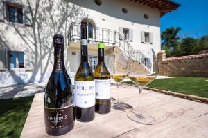 tre bottiglie di vino e due bicchieri su un tavolo di legno di Borgo Gradis'ciutta a Gorizia