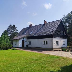 une grande maison blanche avec un toit noir dans l'établissement Powrócisz tu..., à Sorkwity