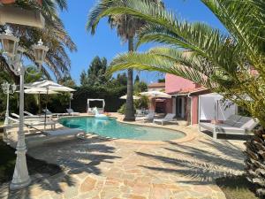 聖馬克西姆的住宿－Fantastic pool villa 900m to the beach; with extravagant big garden，庭院内一个带椅子和棕榈树的游泳池